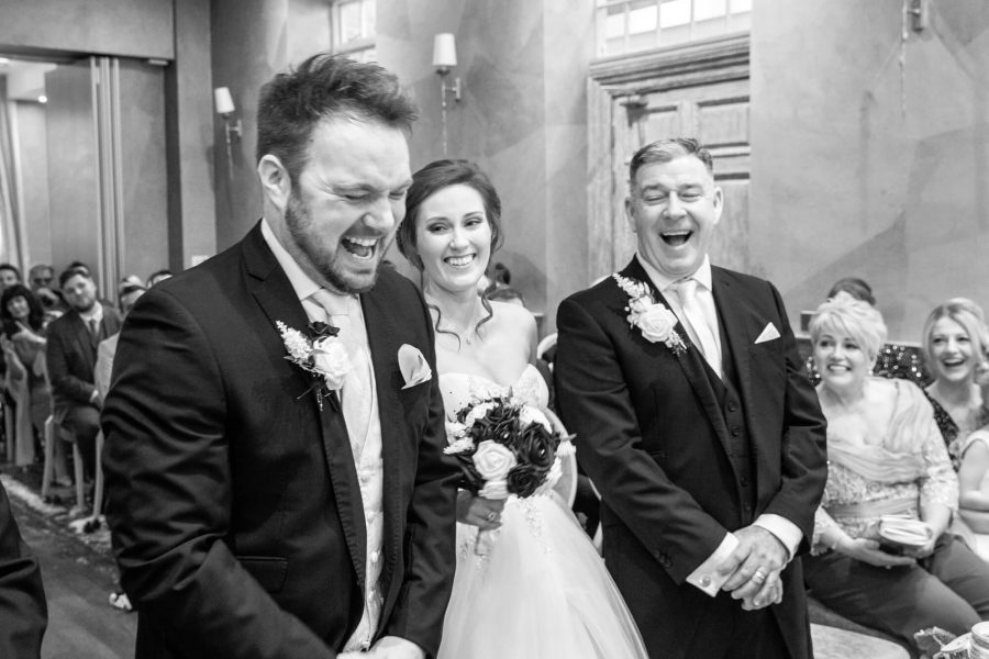 civil wedding ceremony showing a laughing groom, bride and bride's father at fawsley hall, northamptonshire